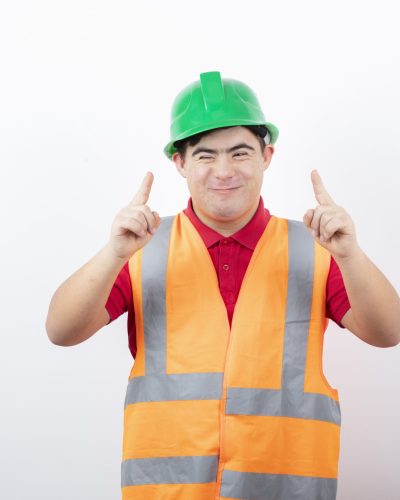 Young construction worker in safety vest standing and pointing at somewhere. High quality photo